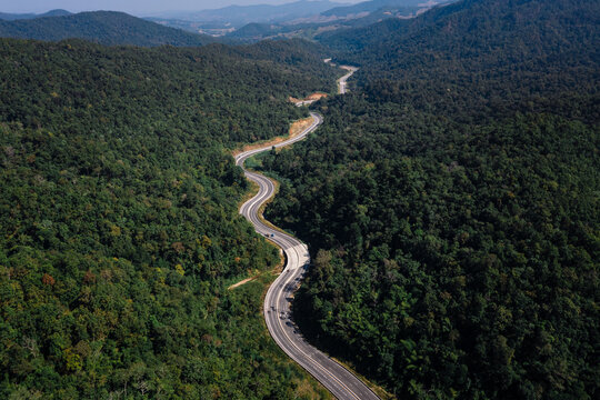 long road curved in valley connecting countryside in the rainforest and the verdant hill forest at northernmost part of Thailand