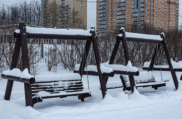 wooden multi-seat swing on the playground in the winter park