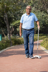 Senior man holding stick while walking at park