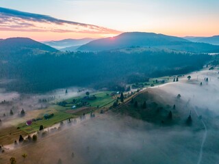 Fog in the mountain valley at dawn. Ukrainian Carpathians in the morning in the haze. Aerial drone...