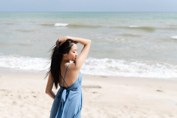 Fototapeta na wymiar Beautiful woman wearing blue dress,standing on the beach,