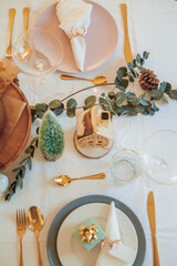 Stylish light Christmas table setting with golden cutlery. Festive feasts. Decorations on the New Year's table.