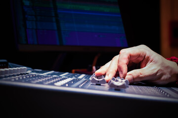 close up sound engineer hands adjusting control surface mixer in recording, broadcasting studio