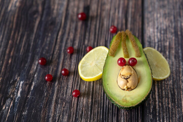 Funny face made from avocado, cranberry and lemon on a wooden background.