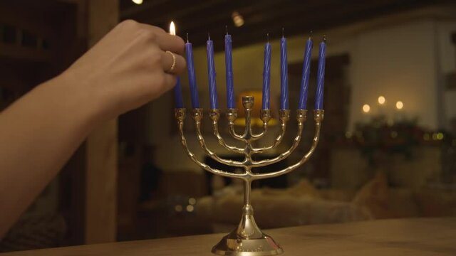 Close Up Shot of Female Hand Lighting Candles On Menorah During Hanukkah Celebration. High quality video footage