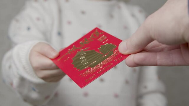 Close Up Shot of Hand Giving Chinese New Year Red Envelope to Child. 