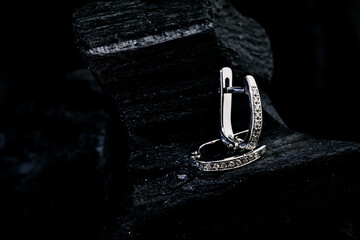 A subject shot of Diamond earrings on a black charcoal background. White gold