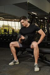Fototapeta na wymiar young man shakes biceps while sitting on sports equipment