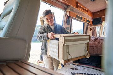 A young man organizing luggage inside a camping car
