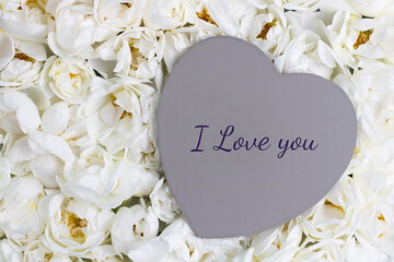 Mockup wooden grey heart for design with text I love you as example on blooming white roses wall. Full bloom background, decoration and flora design. Carpet of flowers. Wedding and St. Valentine's day