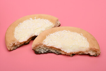 Broken cookie with coconut shavings on pink background