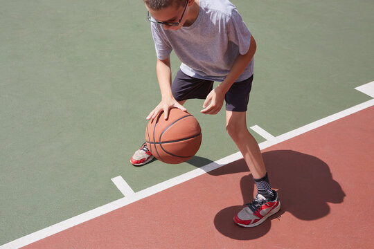 Boy (8-9) dribbling basketball in park