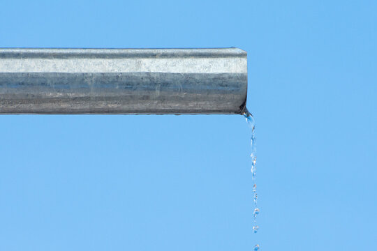 A Trickle Of Water Pours Out Of The Drain. Rainwater Flows From The Roof Through The Gutter.