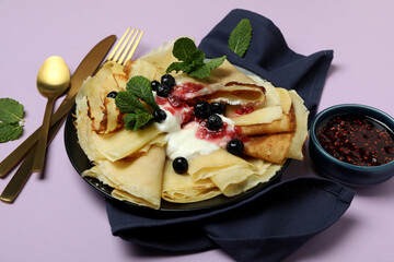 Concept of tasty food with crepes on purple background