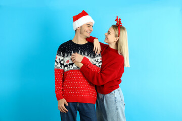 Obraz premium Cute couple in Christmas clothes on blue background