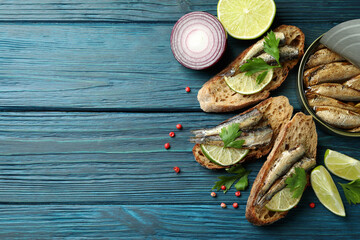 Concept of tasty snack with sandwiches with sprats on wooden background