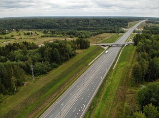federal Highway bridge in summer forest. modern straight road track. Moscow Saint Petersburg motorway M11 Neva in Russia. Aerial drone view. Flying over. 