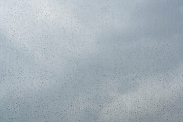 raindrops or water drops on window against soft blue sky