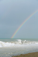 Beautiful seascape off the coast with rainbows, seagulls during storm waves. Vertical photo