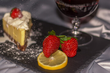 Summer still life with wineglass of champagne, strawberry cheesecake.  Intimate romantic celebration in quarantine.
A beautiful fresh strawberry layer cake with a glass of white wine.