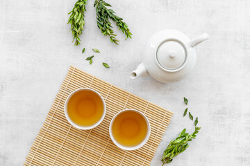 Tea drinking with white teapot and two cups with green leaves, top view