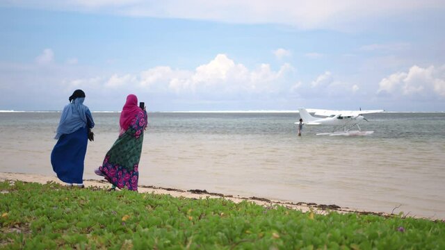 Women in a burqa with her head covered on the beach and looks out at the sea. Arab women take a photo of the ocean