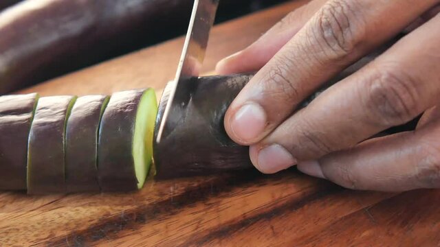 cutting eggplant on a chopping board 