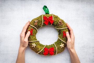 Woman hands holding Christmas wreath with fir tree, top view