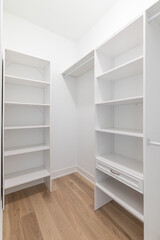 Fototapeta na wymiar Closet shelving with white walls and shelves and hardwood flooring.