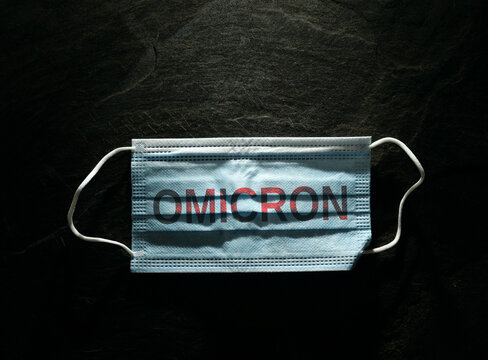 Blue surgical face mask with Omicron text on black background  --  Coronavirus PPE
