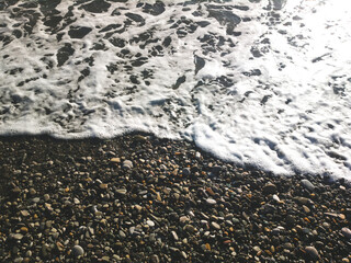 Sea stones, pebbles, sea foam, pebbles on the seashore, water splashes on stones, background with wet stones, sea pebbles on the beach, sea wave on pebbles