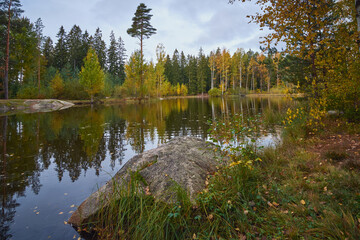 Ollilanlampi pond in autumn in Finnish Kerava: colorful forest, granite stones.