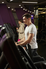 young man and woman are engaged in the gym on an elliptical trainer
