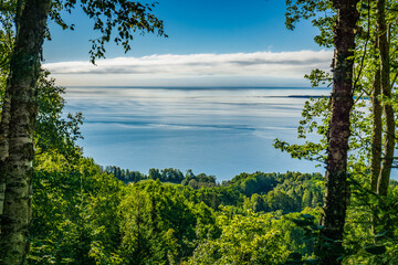 Fototapeta na wymiar View on the St Lawrence river and the Isle-aux-Coudres Island on a summer day from the Foret Marine hiking trail in St Joseph de la Rive, in Charlevoix, a region of Quebec, Canada