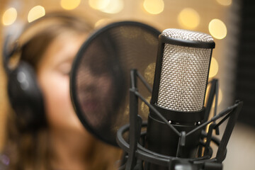 Recording concept. shot of professional microphone at sound record studio, close up. A girl sings into a microphone