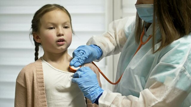 Female doctor listens with a phonendoscope to a girl patient 7-8 years old patient. Pediatrics.