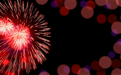 Festive red fireworks on background black sky with bokeh and copy space. Concept of holiday