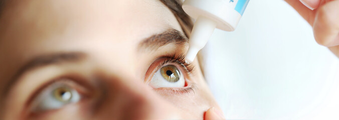 Woman applying eye drop. Vitamin drops from tiredness and redness eyes. Suffering from irritated eye, optical symptoms.