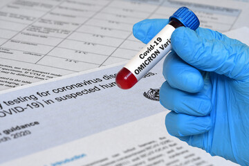 Doctor holds blood test tube for the detection of the Omicron variant of the Covid-19 virus on papers documents.