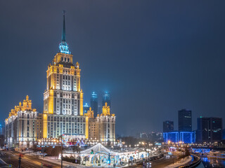 Fototapeta na wymiar Illuminated high-rise stalinist building near river at winter night in Moscow, Russia. Historic name is Hotel Ukraine.