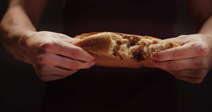 A man tears a loaf of freshly baked bread in half. Home bakery.