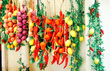 Fototapeta premium Bunches of onions, peppers, garlic hanging on the wall. Sold on the street, Italy