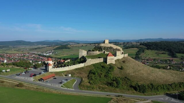 Drone shot fly away of Rupea fortified citadel in Brasov, Romania. Classic Transylvania medieval fortress, aerial view. 