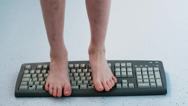 child stands, jumps, dances with his feet on computer keyboard, presses buttons, little vandal, bully plays with gadget, bullying concept, spoils technology until parents can see