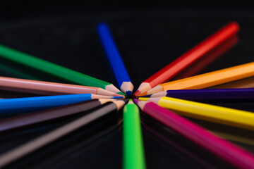 Fototapeta premium Group of colored pencils in a circle on a black background
