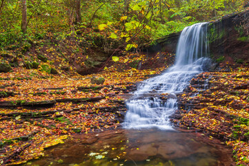 Fototapeta na wymiar Beautiful waterfall on a mountain stream. Beautiful autumn landscape. Location: Rusyliv, Ternopil region, Ukraine
