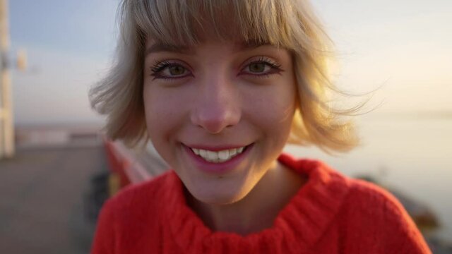 close up outdoor portrait of funny pretty teenage blond girl, smiling in a silly way, grimacing, urban girl portrait