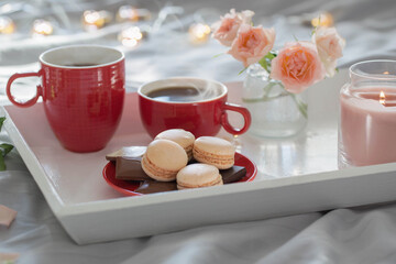 two red cups of coffee and flowers on bed