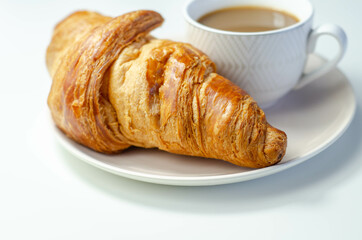 Croissant with chocolate on a plate with coffee in a cup