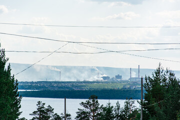 Smoking chimneys of factories on the river bank. Emissions of air pollutants. Environmental...